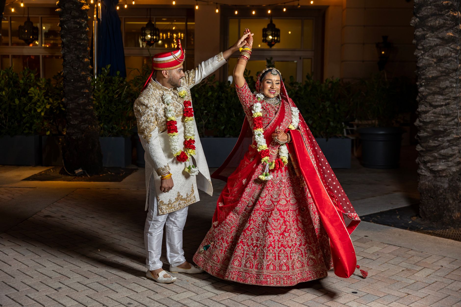 A joyful Indian couple dancing during their wedding ceremony at night, adorned in traditional attire