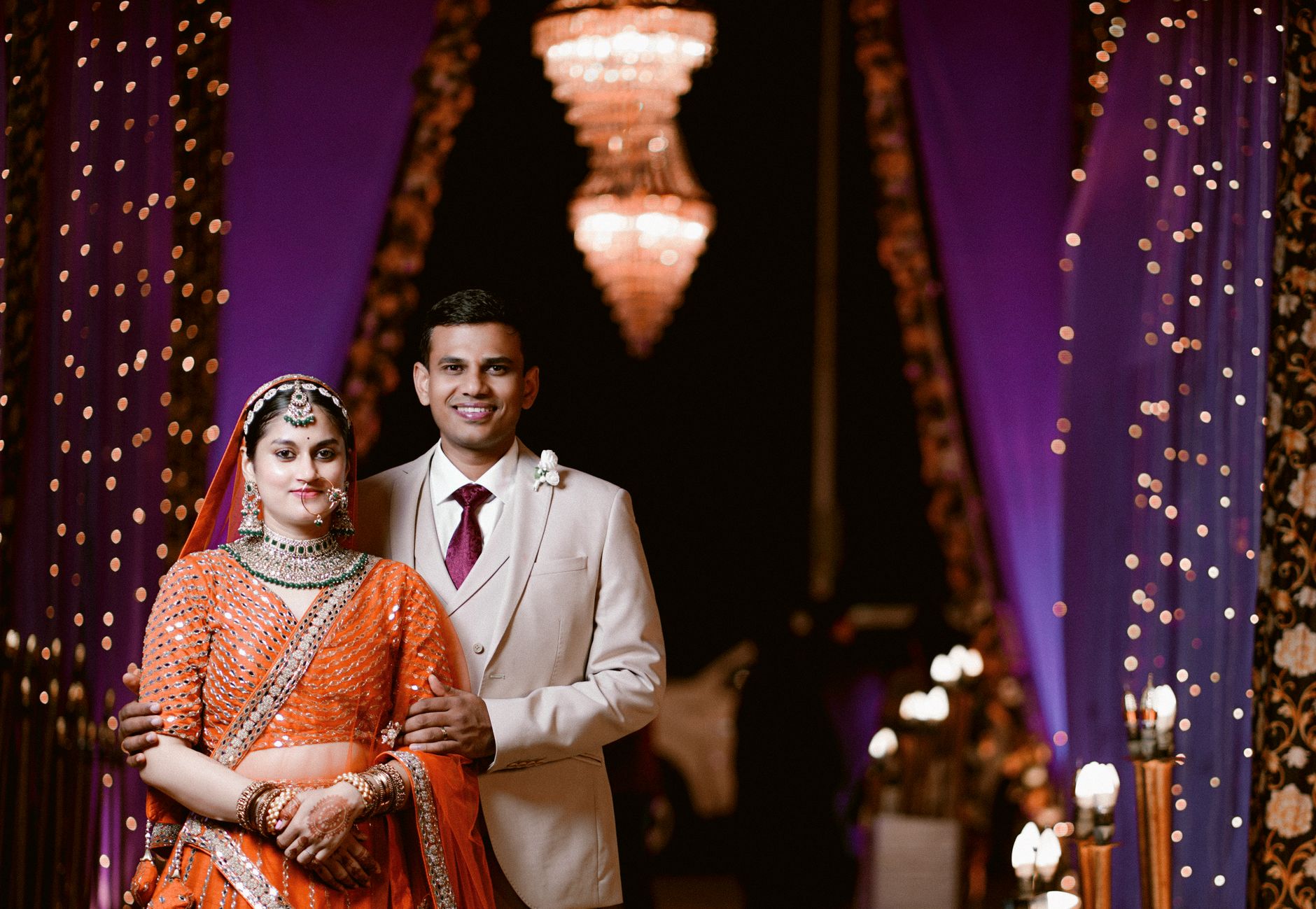 A couple dressed in traditional attire posing elegantly during a wedding ceremony indoors